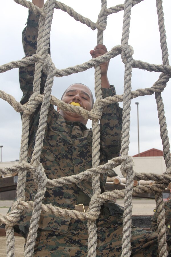 Company H recruits climb the cargo net April 23 aboard Marine Corps Recruit Depot San Diego. This is one of 12 obstacles that recruits had to complete while doing the Confidence Course during week three. The cargo net helps recruits overcome a fear of heights while building up their physical strength.
