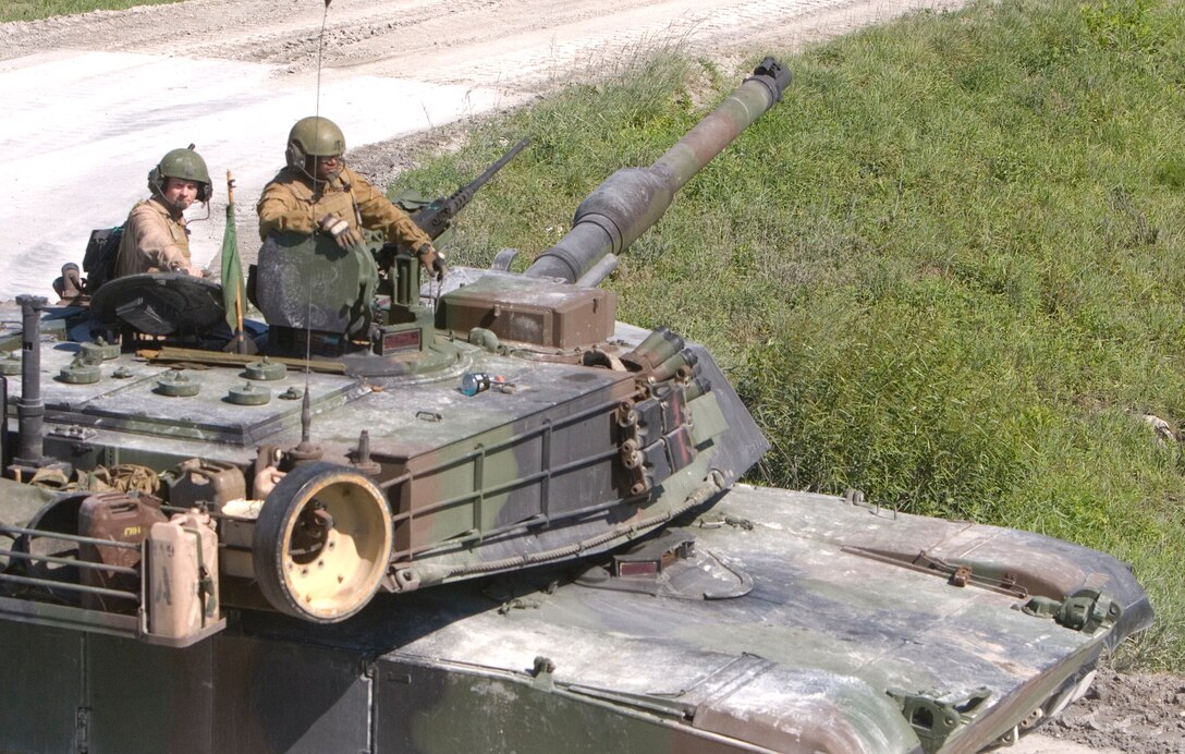 Staff Sgt. Peryck  Smith (right), tank commander and platoon sergeant for 3rd platoon, Company A, 2nd Tank Battalion, 2nd Marine Division, sits atop Blue 4, the fourth M1A1 Abrams tank in 3rd platoon, as it moves into position during the company’s recent  Gunnery Qualifications.  The Jacksonville, Fla., native and his crew won’t know their score until the conclusion  of the entire event, but said they believe they did well.  At one point, they even hit two separate tank targets perfectly in less than 10 seconds while barreling down the track road, an admirable feat for any tank crew.