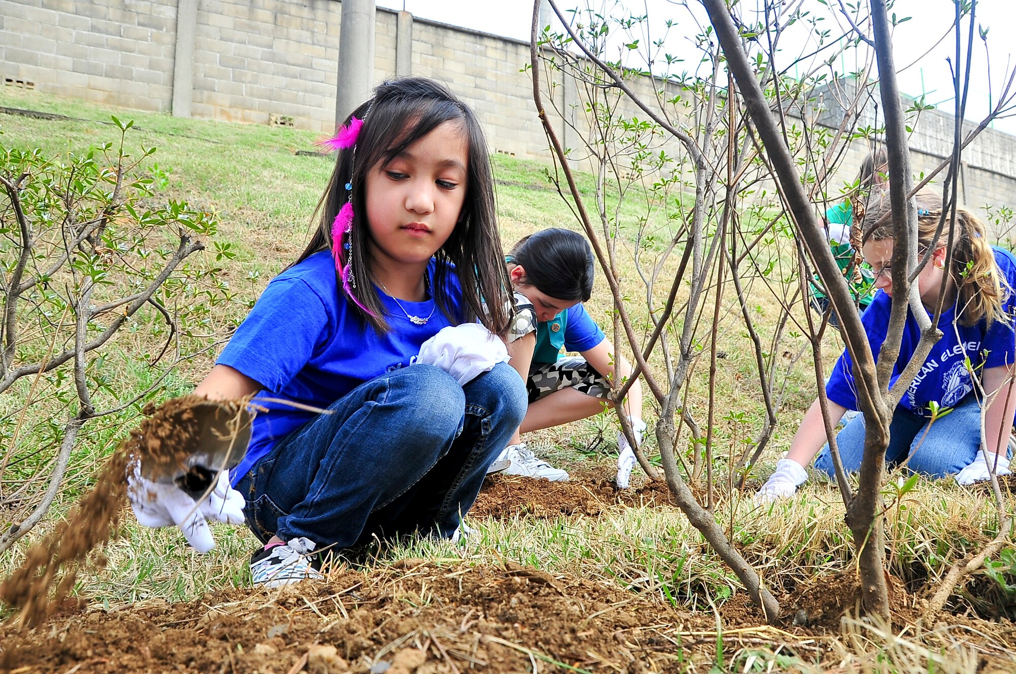 Aaliyah Isidro scoops up dirt to cover up a bush she planted here, April 20, 2012. Approximately 30 Girl Scouts planted more than 200 moss flowers and 10 azalea bushes in honor of Arbor Day and Earth Day to add to the beautification of the perimeter around Osan American Elementary School. Isidro is a 3rd grader from Brownie Troop 11. (U.S. Air Force photo/Senior Airman Adam Grant)