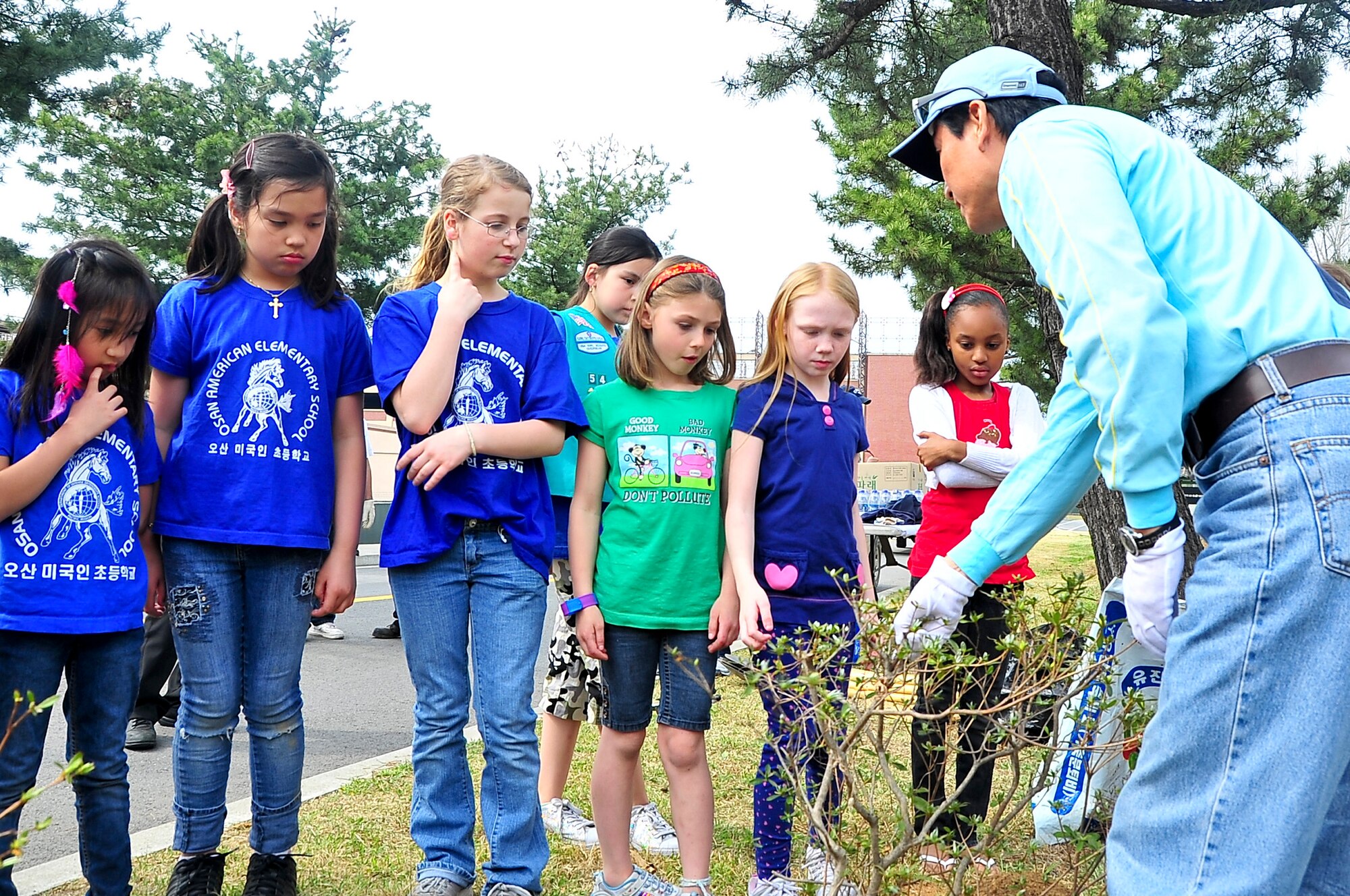 Mr. Song Kun Kwon, 51st Civil Engineer Squadron natural resource manager, shows Osan Girl Scouts how to properly plant bushes in honor of Arbor Day and Earth Day here, April 20, 2012. Approximately 30 Girl Scouts planted more than 200 moss flowers and 10 azalea bushes during the event to add to the beautification of the perimeter around Osan American Elementary School. (U.S. Air Force photo/Senior Airman Adam Grant)