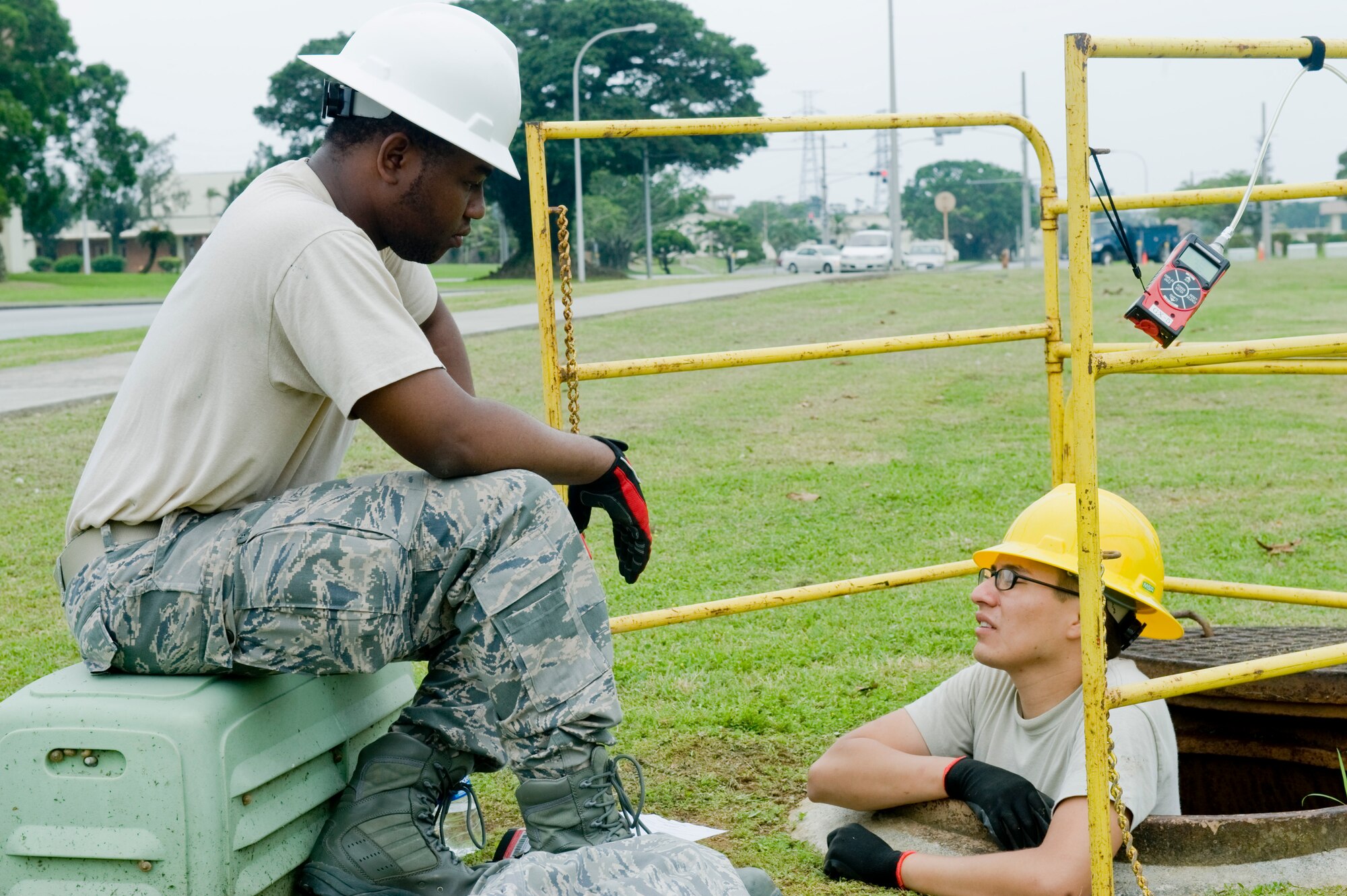 U.S. Air Force Senior Airman Romeo Rivers and Airman 1st Class Oliver Martinez, 18th Communications Squadron cable systems journeyman, take a break from pulling a fiber optic cable through a maintenance hole on Kadena Air Base, Japan, April 24, 2012. The fiber optic cable project will bring high-speed Internet into the Department of Defense Dependent Schools on base. (U.S. Air Force photo by Airman 1st Class Hailey R. Davis/Released)