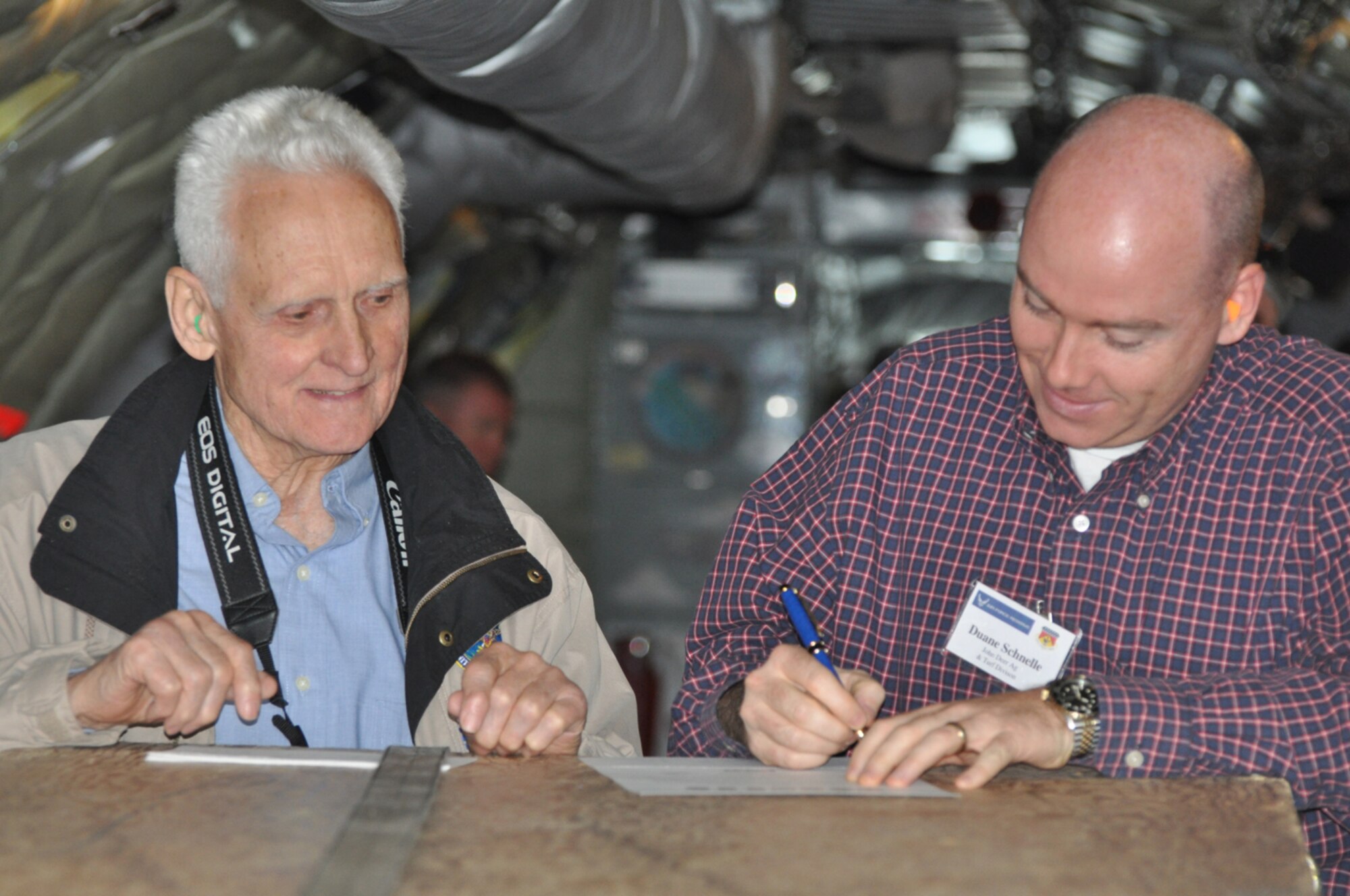 Former NC Employer Support of the Guard and Reserve state chairman Bud Brown smiles as Duane Schnuelle, national sales manager for John Deere, signs a Statement of Support at 20,000 feet during an air-to-air refueling mission with the 916th Air Refueling Wing. U.S. Air Force photo/Maj. Shannon Mann/Released) 
