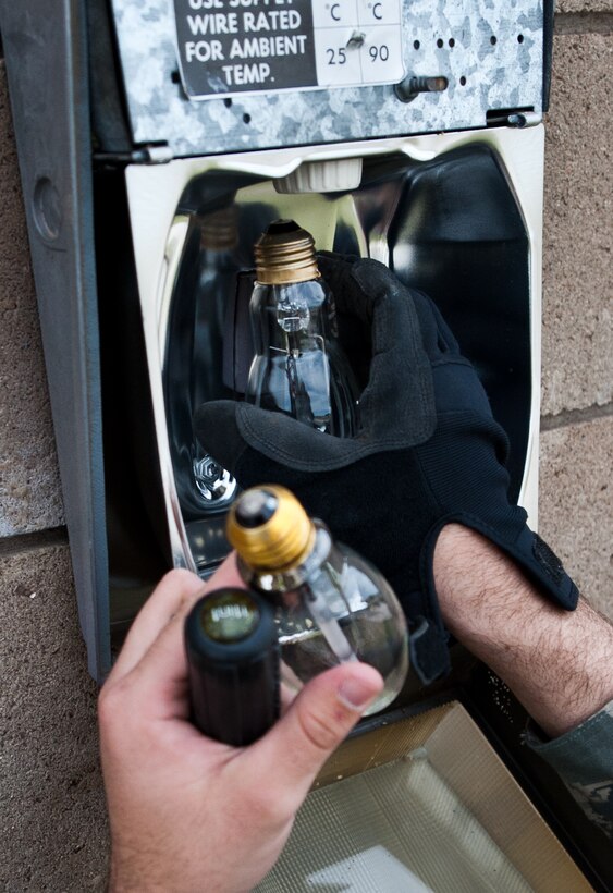 Airman 1st Class Alex Price, 28th Civil Engineer Squadron electrical systems technician, replaces a security light bulb on a maintenance building near the flightline at Ellsworth Air Force Base, S.D., April 20, 2012. The 28th CES electric shop technicians are responsible for the maintenance of all electrical components and lighting on Ellsworth. (U.S. Air Force photo by Airman 1st Class Alystria Maurer/Released)