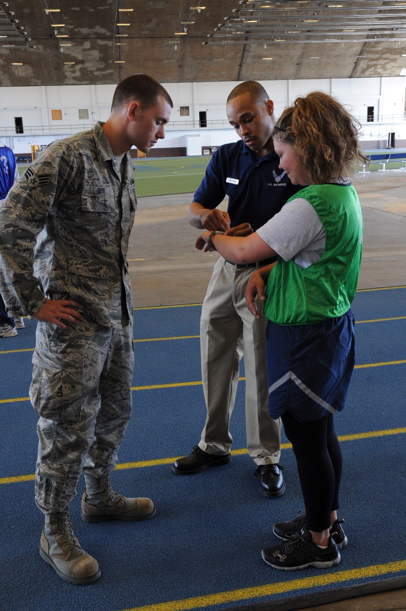 Senior Airman Chris Dye, 28th Maintenance Squadron avionics test station component journeyman, and Staff Sgt. Andre Penn, 28th Force Support Squadron NCO in charge, prepare Senior Airman Melissa Holmes, Air Force Financial Services Center relocations technician/liaison, for the cardio portion of her physical fitness test at the Pride Hangar on Ellsworth Air Force Base, S.D., April 24, 2012. (U.S. Air Force photo by Airman 1st Class Anania Tekurio/Released)