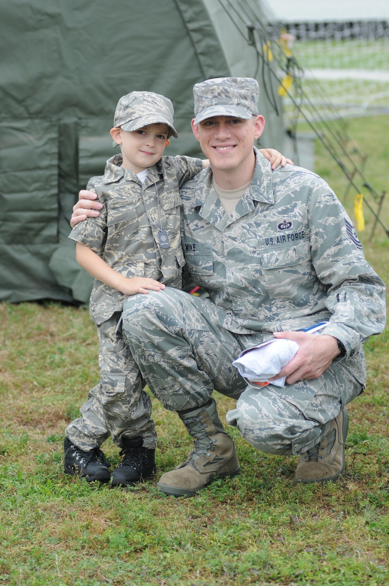 Four-year-old Ezra Mike and his dad, Tech. Sgt. Daniel Mike, 335th Training Squadron, take a photo together showing off their matching airman battle uniforms during Operation Hero building April 21, 2012, at Keesler Air Force Base, Miss.  Operation Hero takes place twice a year. The event was designed to help children better understand what a deployment is and what happens when their parents deploy. (U.S. Air Force photo by Kemberly Groue)