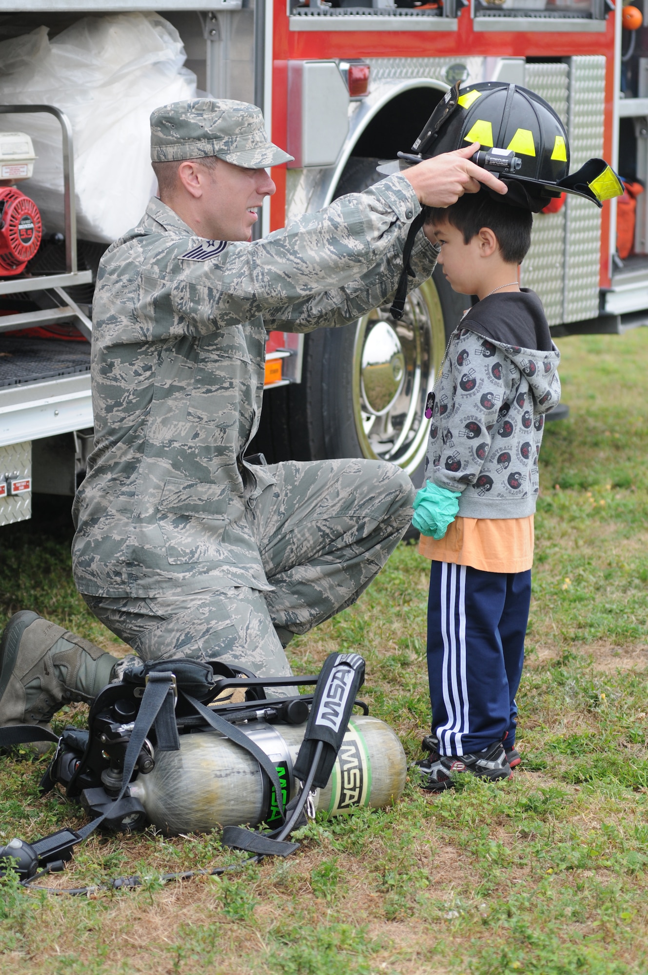 Tech. Sgt. Walter Shutler, 81st Infrastructure Division firefighter, places a firefighter helmet on the head of Lincoln Dooley, 4, during Operation Hero April 21, 2012, at Keesler Air Force Base, Miss.  Operation Hero takes place twice a year. The event was designed to help children better understand what a deployment is and what happens when their parents deploy. Lincoln is the son of Senior Master Sgt. (retired) Darren and Maj. Melissa Dooley, 81st Medical Operations Squadron.  Maj. Dooley is currently deployed to Afghanistan. (U.S. Air Force photo by Kemberly Groue)