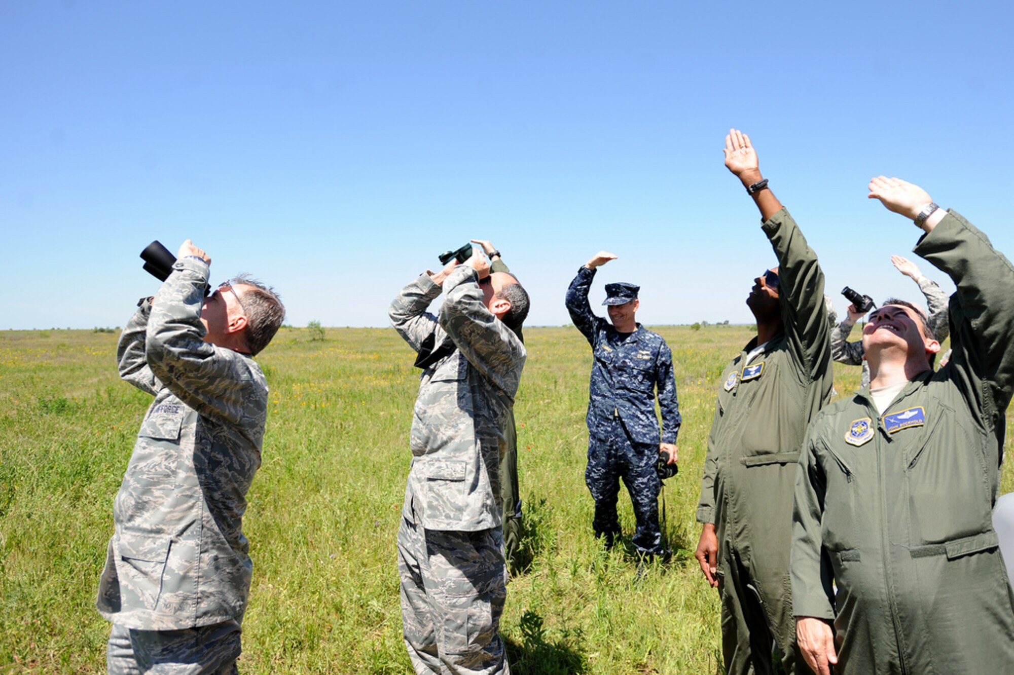 Officials watch as two C-130s release eight Joint Precision Airdrop System (JPADS) bundles during a training exercise Tuesday, April 24, at the Antelope Drop Zone at Fort Hood. The joint exercise was conducted by the Air Force's 317th Airlift Group, responsible for flying the C-130s, and the National Guard's 294th Quartermaster Company, responsible for packing, rigging and loading the bundles onto the aircraft. (Photo by Daniel Cernero, III Corps and Fort Hood Public Affairs)