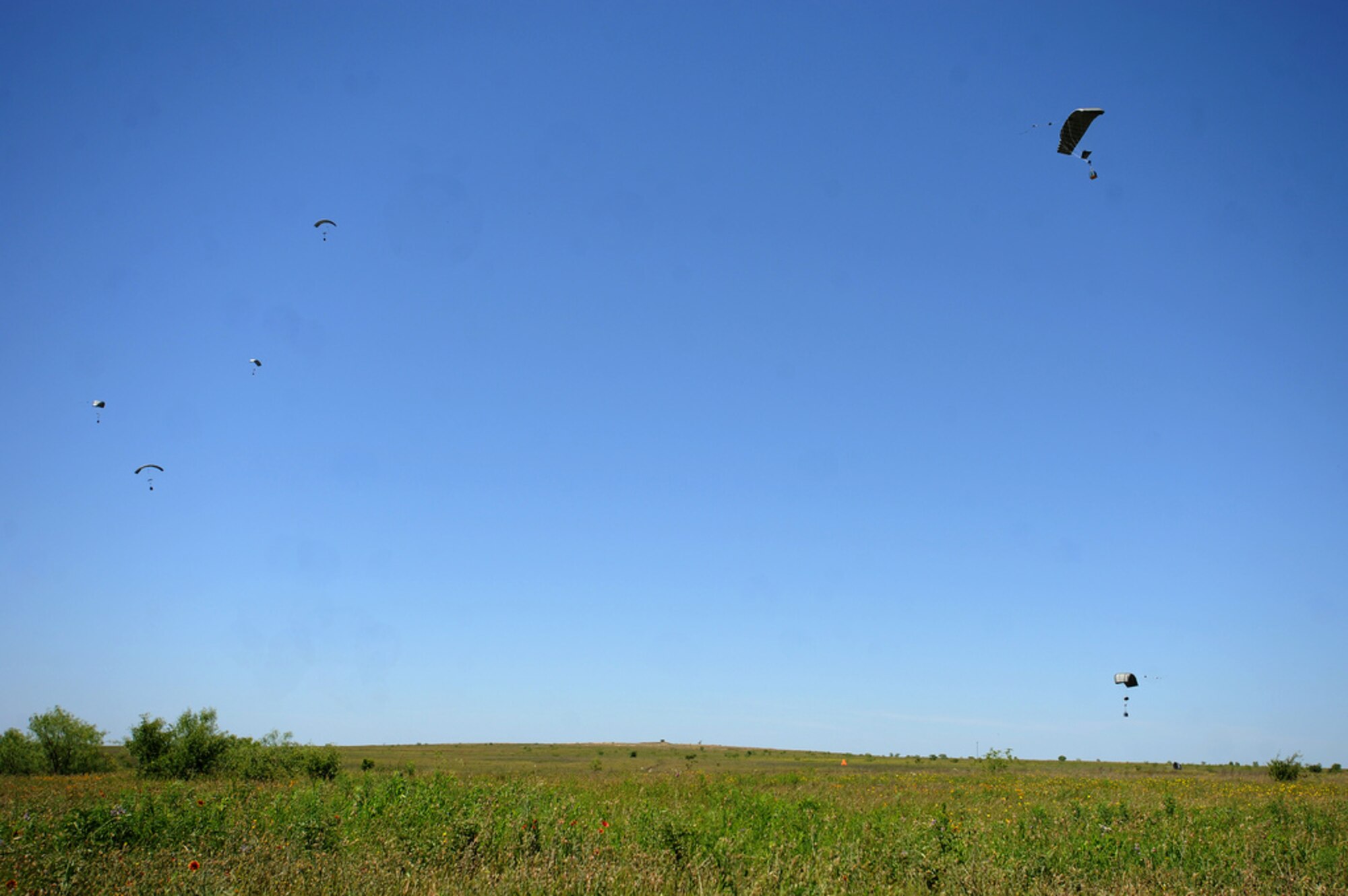 Joint Precision Airdrop System (JPADS) bundles descend to the ground during a training exercise Tuesday, April 24, at the Antelope Drop Zone at Fort Hood. JPADS is an airdrop system that uses Global Positioning Satellite, steerable parachutes and an onboard computer to steer loads to a designated point of impact on a drop zone. (Photo by Daniel Cernero, III Corps and Fort Hood Public Affairs)