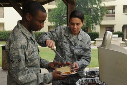 Master Sgt. Andrea Howard, 902nd Comptroller Squadron first sergeant, serves a hot dog to Airman 1st Class Brandon Dixon, Air Force Personnel Center, at the Joint Base San Antonio-Randolph Dorm Community Council's Pie-in-the-Face cookout April 20. The Randolph First Sergeant's Council sponsored and cooked for the lunch-time event. (U.S. Air Force photo/Rich McFadden) 