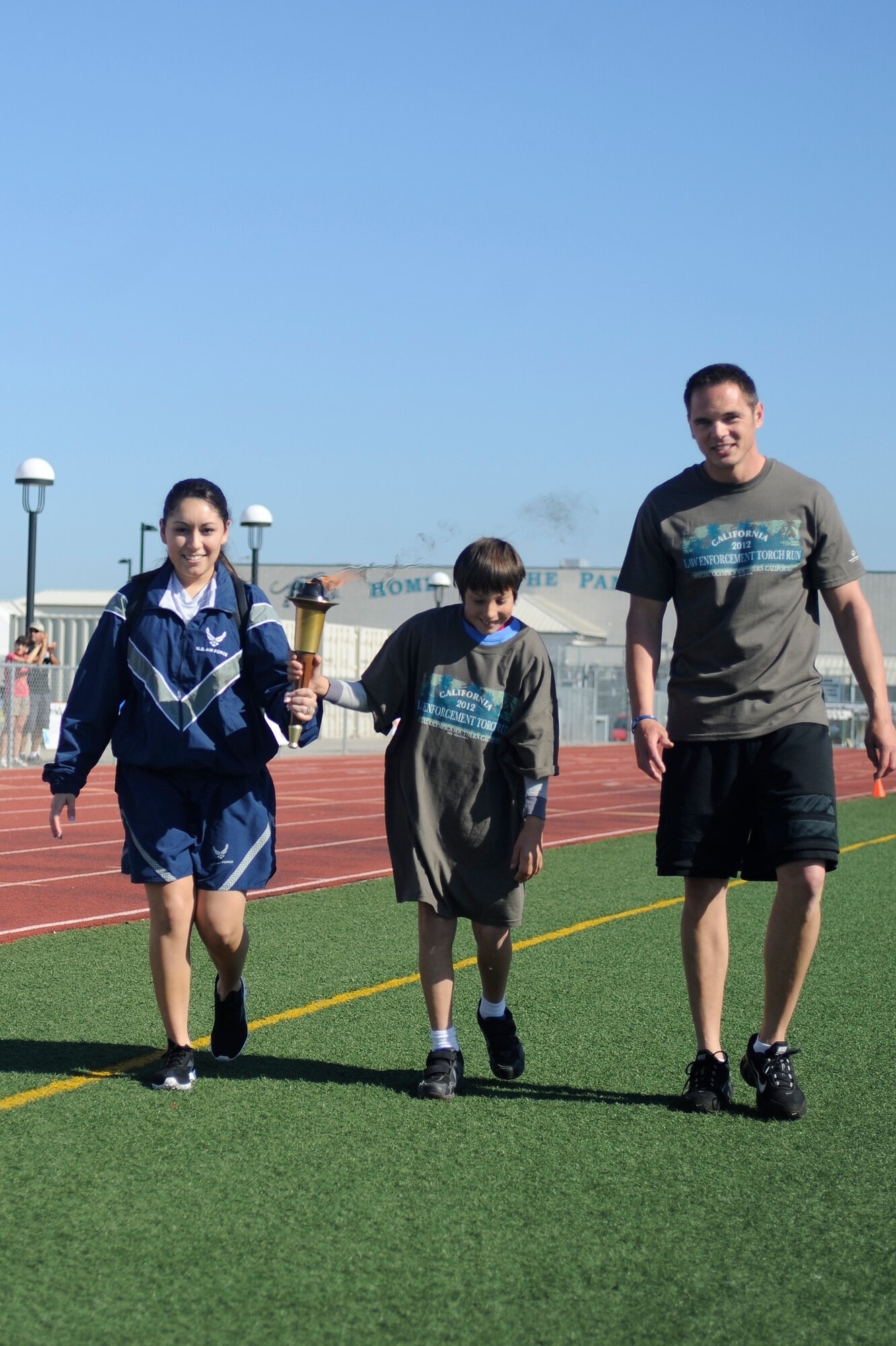 VANDENBERG AIR FORCE BASE, Calif. -- Senior Airman Anna Marie Alarcon, a 9th Space Operations Squadron member, JT Sheehan, a Special Olympics athlete and Officer Nate Totorica, a Santa Maria police officer, walk the final stretch of the torch run during the Northern Santa Barbara County Special Olympics event at Pioneer Valley High School, Santa Maria Saturday, April 21, 2012. The Special Olympics competition is an international event that held their first summer games in Chicago, Ill. July 1968. (U.S. Air Force photo/Staff Sgt. Andrew Satran) 

 