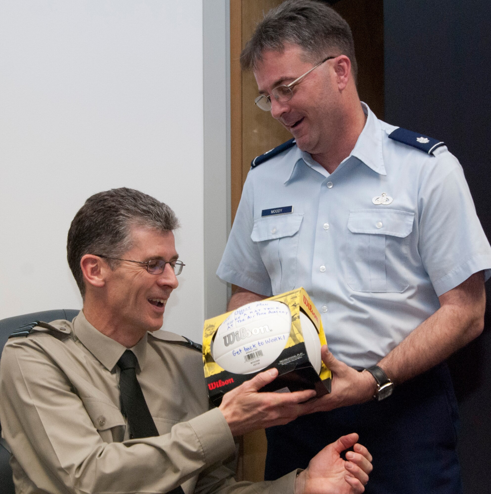 Lt. Col. Eric Moody (right) presents Royal Air Force Squadron Leader Martin Harris with a ball celebrating his feat as "the oldest man to score a (football) hat trick at the Air Force Academy" during a send-off for the RAF exchange officer April 20, 2012. Harris' departure marks the end of the 55-year exchange program between the Academy and its British counterpart, the Officer and Aircrew Cadet Training Unit, at RAF College Cranwell, England. Moody is an instructor with the Academy's Military and Strategic Studies Department. (U.S. Air Force photo/Don Branum)