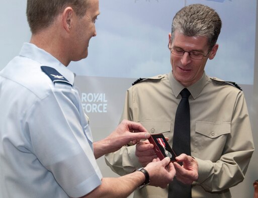 Col. Thomas Drohan presents Royal Air Force Squadron Leader Martin Harris with a Queen's Diamond Jubilee Medal during a RAF officers send-off in the Air Force Academy Cadet Battle Lab April 20, 2012. The medal was instituted Feb. 6, 2012, to commemorate 60 years of Queen Elizabeth II's reign. Harris is the outgoing RAF exchange officer to the Academy. Drohan is the head of the Academy's Military and Strategic Studies Department. (U.S. Air Force photo/Don Branum)