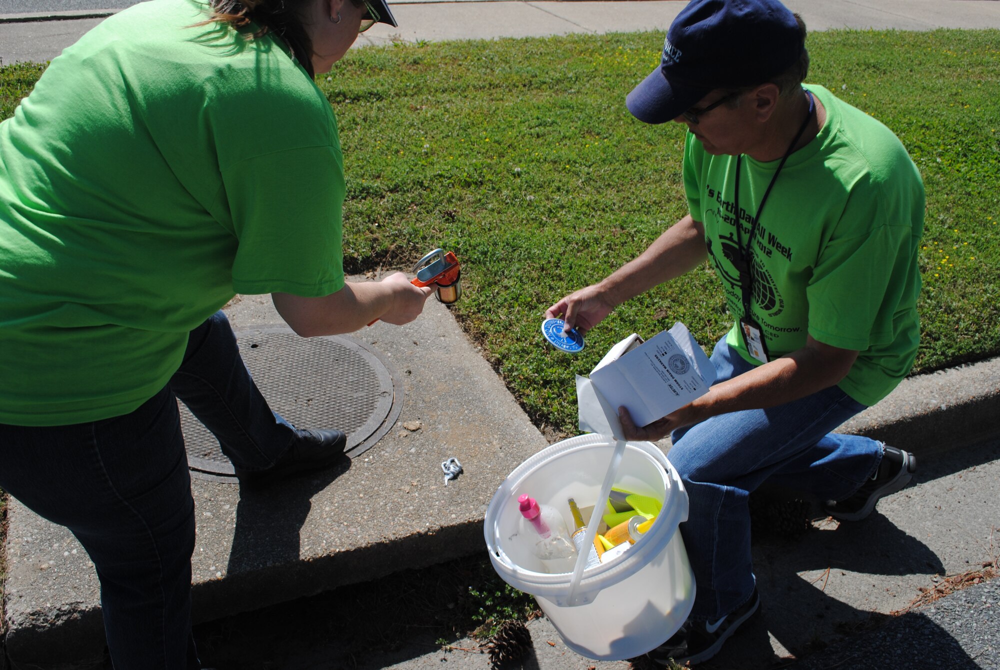 Tracy Campbell with the Army Training Support Center and Lawrence Hadsell with the 362nd Training Squadron, Detachment 1, walk Fort Eustis, Va., April 16, looking for storm drains to affix medallions that warn people to not dump in storm drains. Numerous communities celebrate Earth Week, an entire week of activities focused on environmental issues. (Courtesy photo by Toni Guagenti/Released)