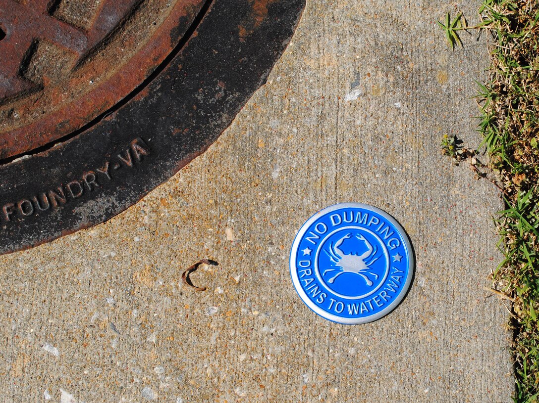 A newly-cemented medallion near a storm drain on Fort Eustis, Va., reminds people not to dump anything in storm drains; the water leads directly to the Chesapeake Bay. Earth Day is an annual day on which events are held worldwide to increase awareness and appreciation of the Earth's natural environment. (Courtesy photo by Toni Guagenti/Released)