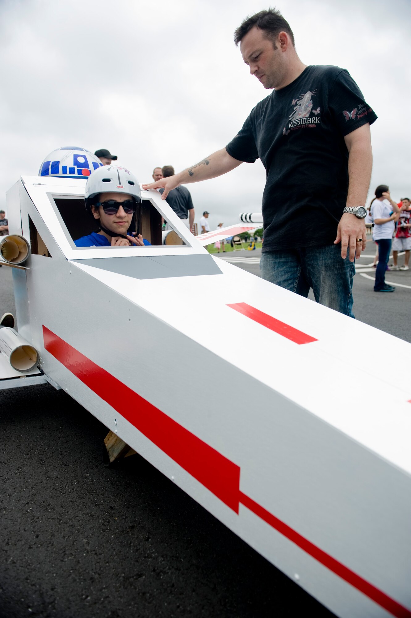 Master Sgt. David Petty, 18th Logistics Readiness Squadron, helps derby driver Lauren Cruz get ready for a his race during the Red Cross Derby Day at Kadena Air Base, Japan, April 24, 2012. The derby raised $5,200 for island-wide community service projects for U.S. service members and their families. (U.S. Air Force photo by Staff Sgt. Jonathan Steffen/Released)