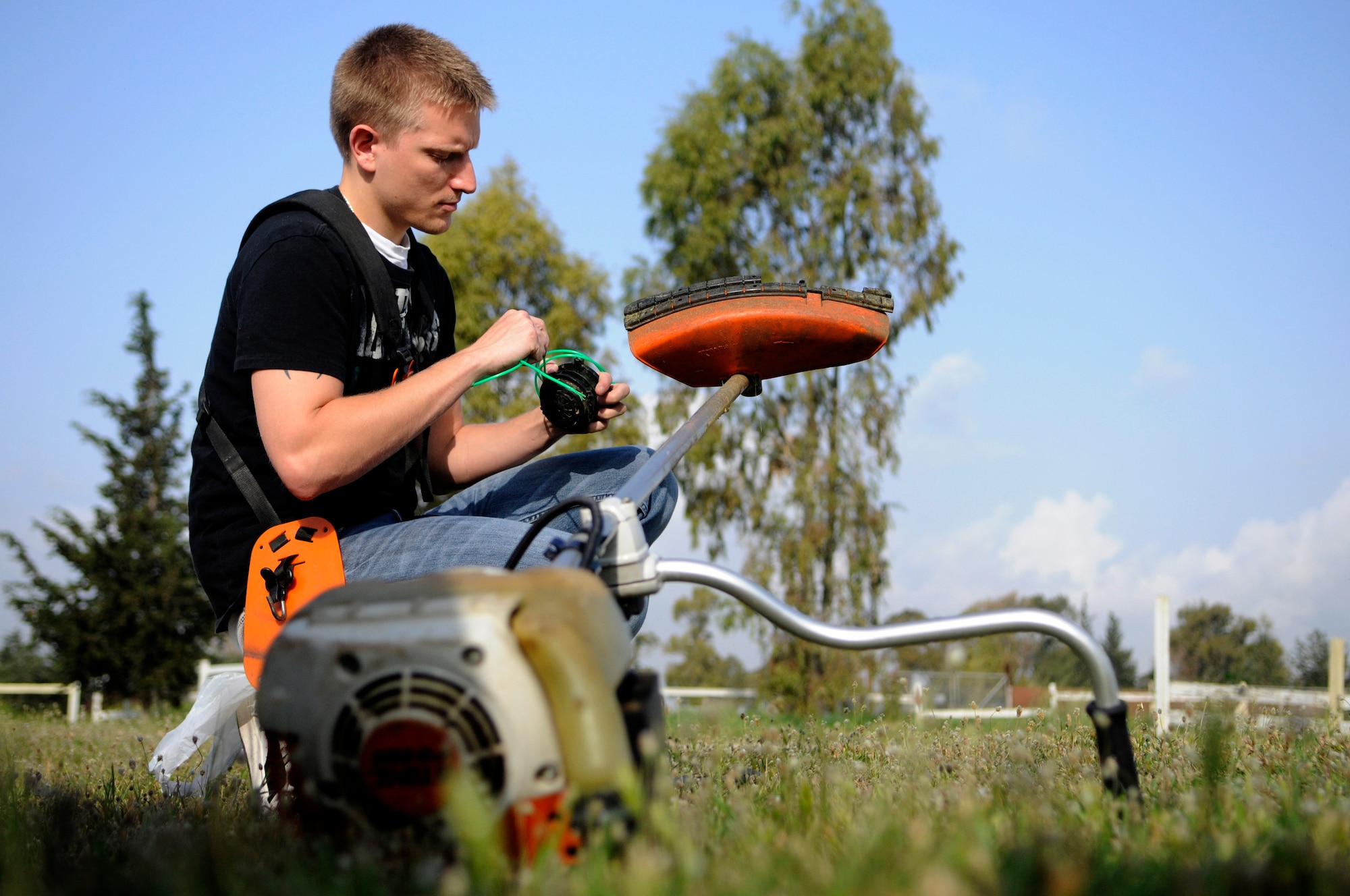 Senior Airman Christopher Tolczyk, 39th Logistics Readiness Squadron, fixes the line on a trimmer at the base dog park April 21, 2012, at Incirlik Air Base, Turkey. Twelve volunteers spent five hours gathering trash and debris, mending fences, and mowing to provide a place for the base's furry residents to play. (U.S. Air Force photo by Staff Sgt. Kali L. Gradishar/Released)