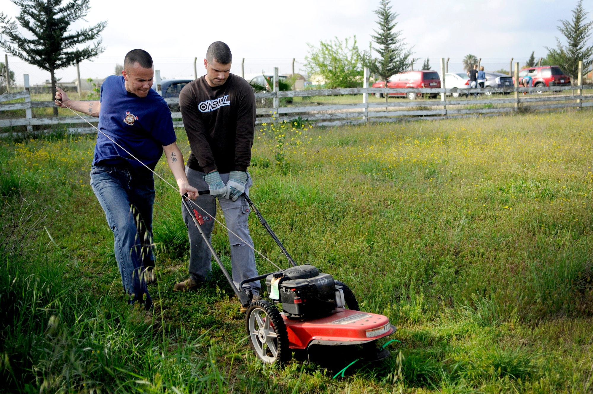 Staff Sgt. Kitsana Dounglomchan, 39th Force Support Squadron, left, and Staff Sgt. Paul Melicia, 39th Security Forces Squadron, try to start a mower at the base dog park April 21, 2012, at Incirlik Air Base, Turkey. Twelve volunteers spent five hours gathering trash and debris, mending fences, and mowing to provide a place for the base's furry residents to play. (U.S. Air Force photo by Staff Sgt. Kali L. Gradishar/Released)