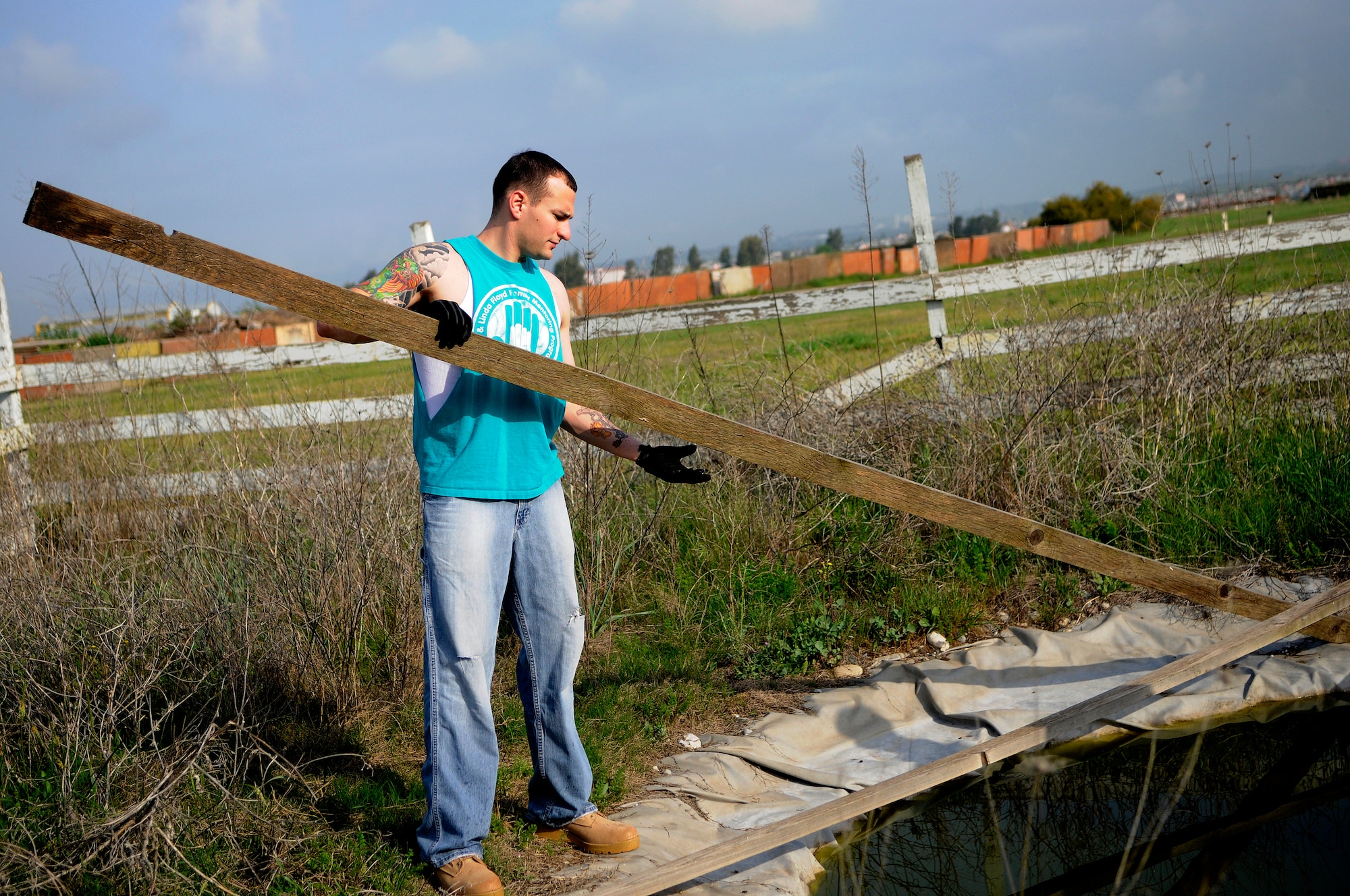 Staff Sgt. Kevin Kirk, 39th Logistics Readiness Squadron, removes fence boards from a pond at the base dog park April 21, 2012, at Incirlik Air Base, Turkey. Twelve volunteers spent five hours gathering trash and debris, mending fences, and mowing to provide a place for the base's furry residents to play. (U.S. Air Force photo by Staff Sgt. Kali L. Gradishar/Released)