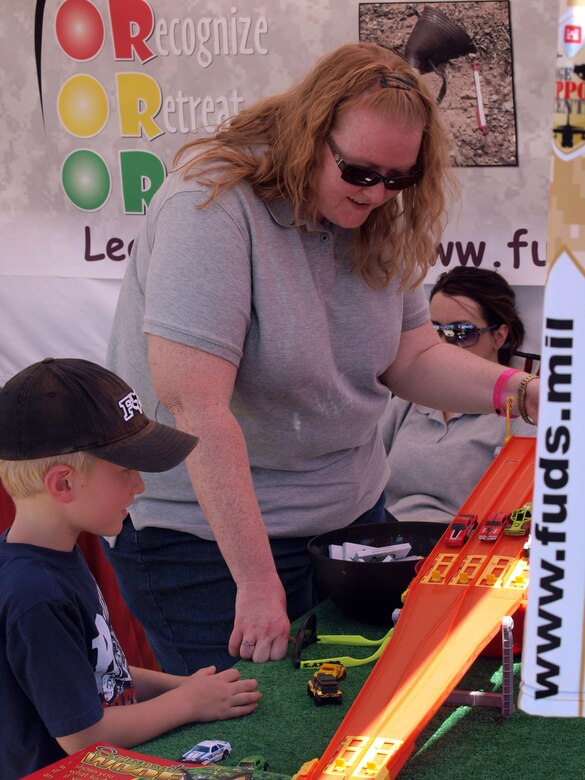 Heather Rogers of Bristol Environmental Remediation Services speaks with a young participant about the 3Rs of explosives safety. The finish line and prizes reflect the programs key message: Recognize, Retreat and Report. 
  