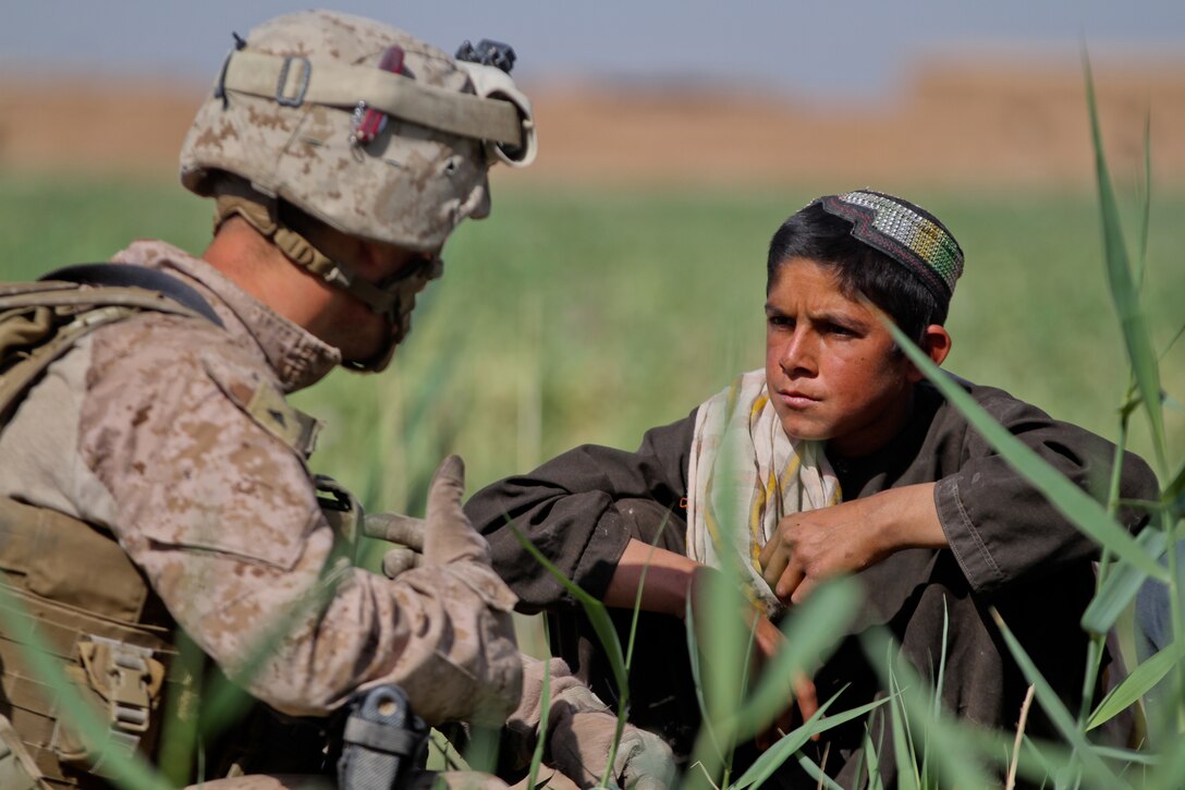 Lance Cpl. John Ellington, a team leader with Weapons Company, 2nd Battalion, 6th Marine Regiment, talks to a local Afghan boy about the area, April 24, 2012. Ellington’s platoon partnered with Afghan soldiers in a clearing operation throughout the area.::r::::n::::r::::n::::r::::n::
