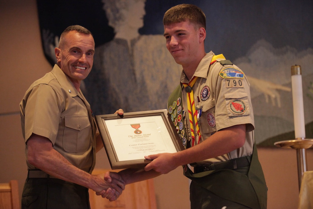 Brig. Gen. Vincent A. Coglianese, commanding general of Marine Corps Installation West - Marine Corps Base Camp Pendleton presents the 'Honor Medal with crossed palms' certificate to Connor F. Stotts, an Eagle Scout with Camp Pendleton's Boy Scout Troop 790. Stotts was presented the coveted Boy Scouts of America 'Honor Medal with crossed palms'. Stotts was awarded the medal in recognition for single handedly saving the lives of three swimmers, July 31, 2011.