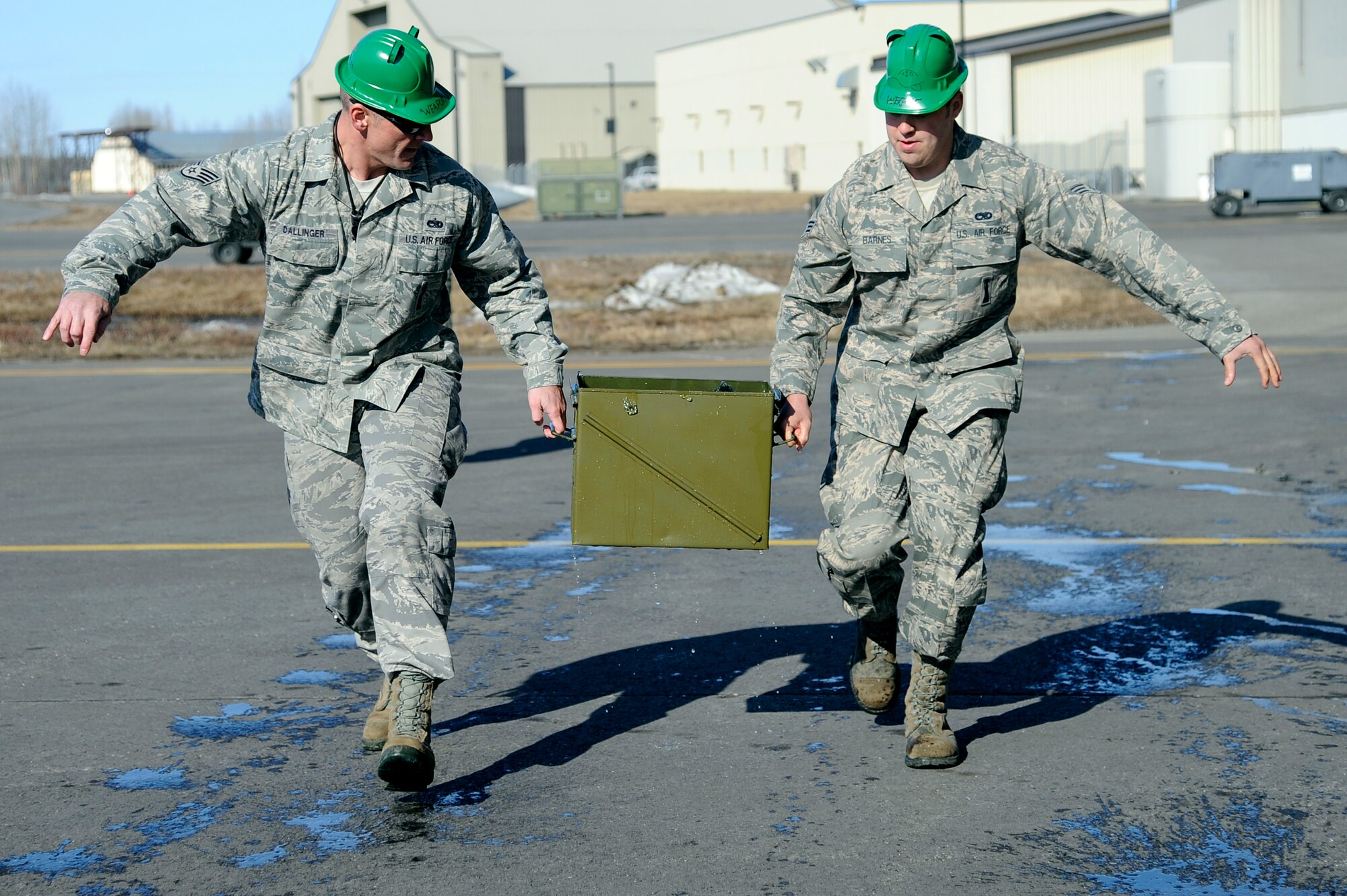 U.S. Air Force Staff Sgt. Brett Dallinger, 354th Maintenance Squadron weapons team chief, and Senior Airman Sean Barnes, 354th AMXS weapons load crew member, haul an ammo can during the 354th Maintenance Group Olympics ammo can relay April 20, 2012, Eielson Air Force Base, Alaska.  The ammo can relay pushed teams to quickly transport water-filled ammo cans a set distance without losing water. (U.S. Air Force photo/Staff Sgt. Jim Araos)