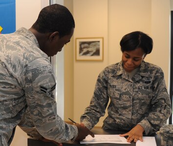 Airman 1st Class Jamal Snow assists Airman 1st Class Londone Yates at Joint Base Charleston - Air Base April 10. The 628th Communications Squadron processes 100 to 200 pieces of official mail a day. Snow is a 628th CS knowledge operations management journeyman. (U.S. Air Force photo/ Airman 1st Class Chacarra Walker)