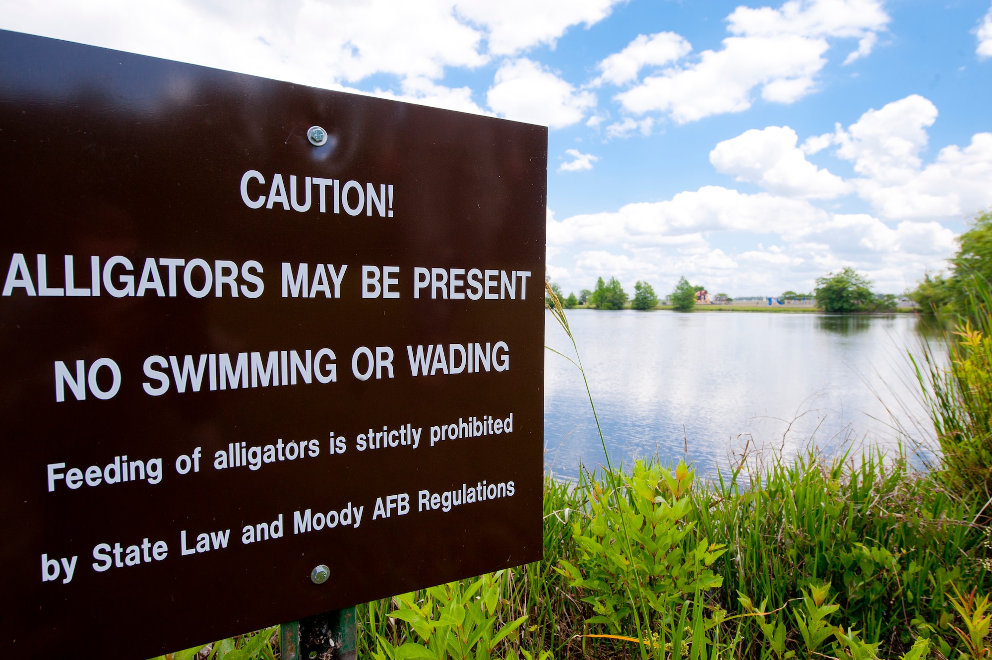 A caution sign at Mission Lake on Moody Air Force Base, Ga., warns visitors of alligators in the area. Alligators may become a danger when they lose their fear of humans, which can happen when they are fed. (U.S. Air Force photo by Airman 1st Class Jarrod Grammel/Released)
