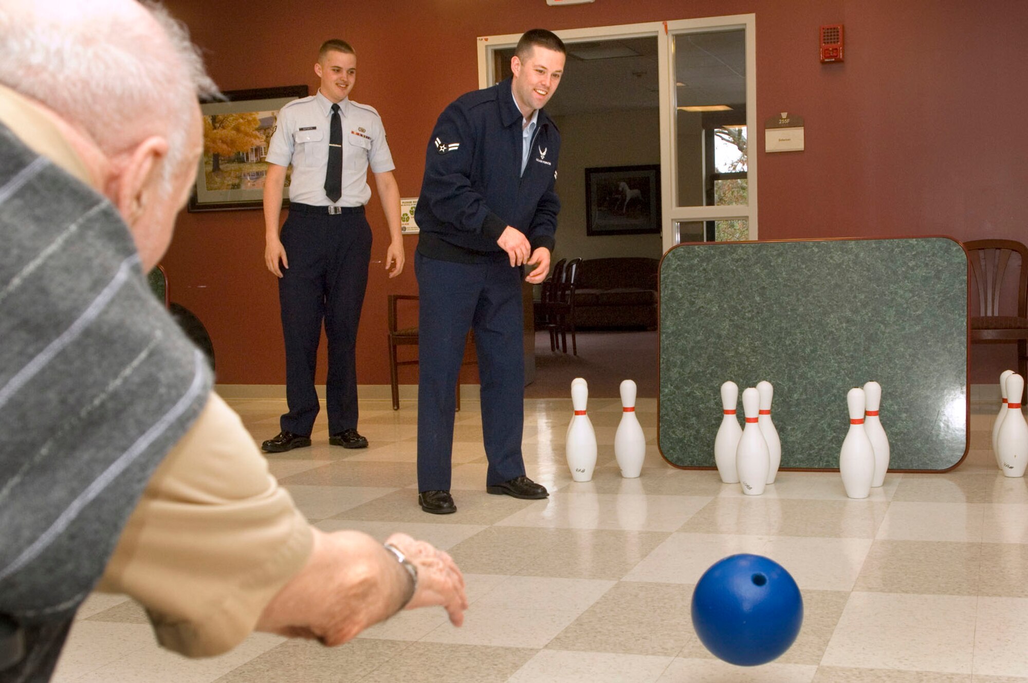 BEDFORD, Mass. -- Airman 1st Class John Fay cheers on a resident during a bowling activity at the Bedford Veteran's Hospital April 23 as Airman 1st Class Matthew Goforth looks on. Seven volunteers from Hanscom traveled to the hospital to assist with the bowling activity and visit with residents. (U.S. Air Force photo by Mark Wyatt)