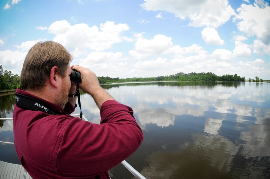 Gregory Lee, 23d Civil Engineer Squadron environmental management chief, looks for alligators at Mission Lake, April 18, 2012, at Moody Air Force Base, Ga. Some of Lee’s responsibilities are to assess and investigate alligator complaints and to coordinate the removal of troublesome  alligators if necessary. (U.S. Air Force photo by Airman 1st Class Douglas Ellis/Released)