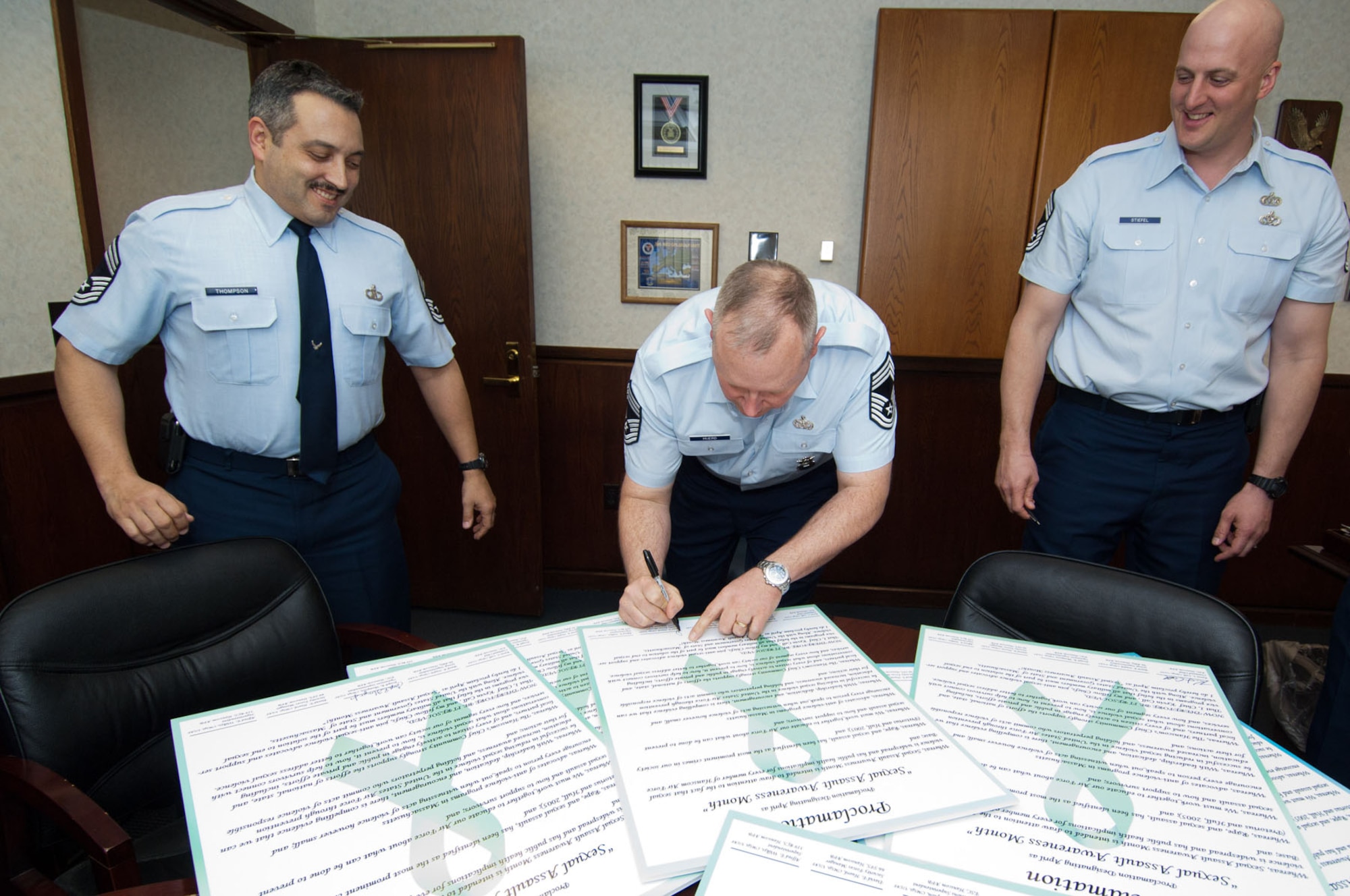 HANSCOM AIR FORCE BASE, Mass. – Chief Master Sgt. David Huerd, along with Chief Master Sgt. Joe Thompson (left) and Chief Master Sgt. Baird Stiefel (right), as well as other male chiefs from the base, sign a proclamation declaring they will stand up against sexual violence and support service programs not only in April, but throughout the year as part of Sexual Assault Awareness Month. The signed proclamations can be seen throughout the base. (U.S. Air Force photo by Rick Berry) 