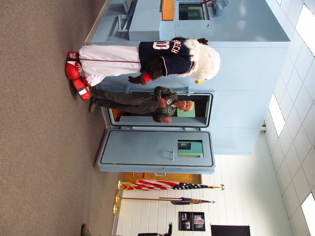 Lt. Col. Michaela Demboski, flight commander, Aerospace and Operational Physiology, shows Screech the altitude chamber April 24. The altitude chamber is intended to show aircrews what an extreme environment feels like. The footage shot will be shown at an upcoming baseball game on May 16. (Air Force Photo by Melanie Moore)