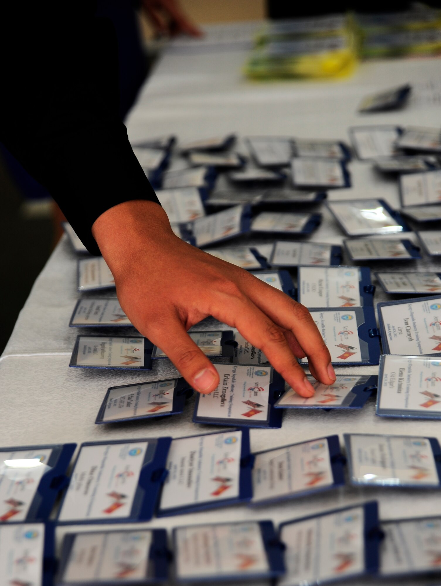 A participant of the Kyrgyzstan Industry Training Symposium searches for his name tag April 24, 2012, in Bishkek, Kyrgyzstan. Attendees received information regarding opportunities and requirements for working with representatives of the U.S. government including the 376th Expeditionary Contracting Squadron at the Transit Center at Manas, Kyrgyzstan. The past 10 years the Transit Center has been open, the local businesses have seen an increase in sales. On a daily basis, 6,000 copies of Stars and Stripes are printed in Bishkek for distribution on the Transit Center as well as every month $200,000 worth of water is purchased from a local company to support service members and civilian contractors. (U.S. Air Force photo/Staff Sgt. Angela Ruiz)