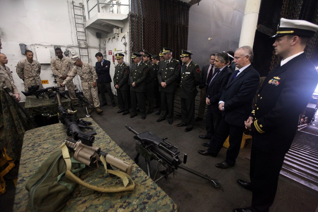 Gunnery Sgt. Jose Martins, the platoon commander for Weapons Platoon, Charlie Company, Battalion Landing Team 1st Battalion, 2nd Marine Regiment, 24th Marine Expeditionary Unit, explains the use of various weapon systems to members of the Albanian military and government April 25, 2012, aboard the USS Gunston Hall. The Albanian visitors were hosted aboard the ship during a port stop in Albania where Marines and Sailors also participated in various tours of the country and assisted in community relations projects.  The 24th MEU, partnered with the Navy's Iwo Jima Amphibious Ready Group, is currently deployed as a theater reserve and crisis response force capable of a variety of missions from full-scale combat operations to humanitarian assistance and disaster relief.