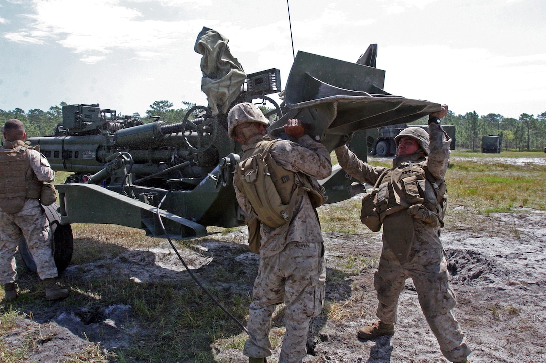 Two Marines with Gun 3, Battery A, 1st Battalion, 10th Marine Regiment, 2nd Marine Division, push one of the legs of an M777 Howitzer into place as they prepare to move the gun line to a new location.  The M777 Howitzer is the primary weapon system for the battalion, which recently spent a week coordinating all of its batteries through firing and movement drills and simulations as part of a battalion-wide training event.  (Official U.S. Marine Corps photo by Lance Cpl. James Frazer)