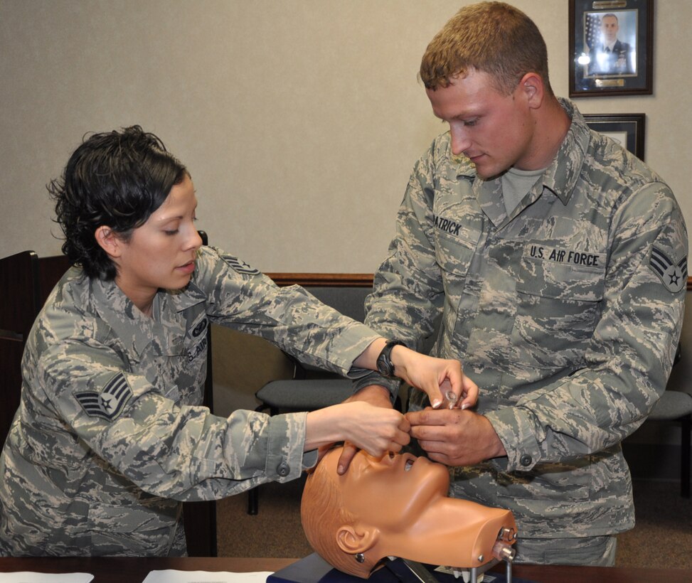 Staff Sgt. Maria Ruiz, Self Aid and Buddy Care instructor, 22nd Air Refueling Wing shows Senior Airman Garrett Patrick, 931st Maintenance Squadron how to properly administer a nasopharyngeal tube during SABC training here, April 26. Nasopharyngeal tubes are used to open airways and restore breathing for injured personnel. Deploying Airmen are issued the tube in their individual first aid kits. Airmen are required to be familiar with all of the contents in their IFAK. (Air Force photo by Tech. Sgt. Brannen Parrish)