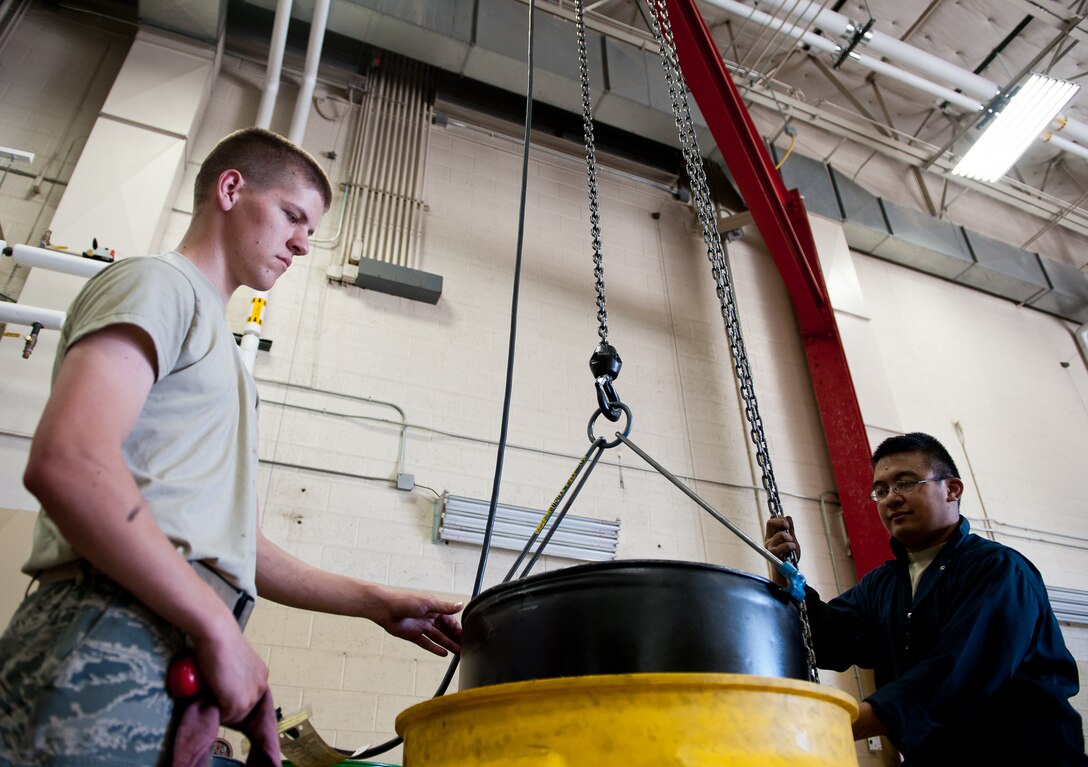 Airman 1st Class Dillion Rickman (left) and Staff Sgt. Agustin Tabita, 28th Logistics Readiness Squadron vehicle and vehicular equipment mechanics, replace an empty oil barrel with a full one during routine maintenance in the vehicle maintenance shop at Ellsworth Air Force Base, S.D., April 24, 2012. Regular maintenance ensures that all 28th Bomb Wing government vehicles operate safely, and are always ready for the mission. (U.S. Air Force photo by Airman 1st Class Kate Thornton/Released) 