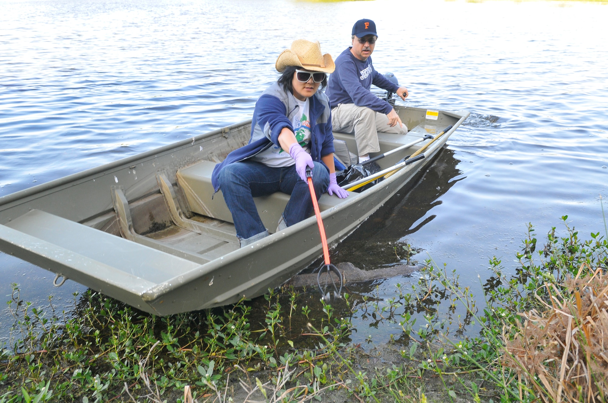 Esther Lee-Altman and Bob Sargent, 78th Civil Engineer Group, use a boat to collect debris from Scout Lake Wednesday. The clean-up was part of the Robins Air Force Base Earth Day Celebration events.( U. S. Air Force photo by Sue Sapp)