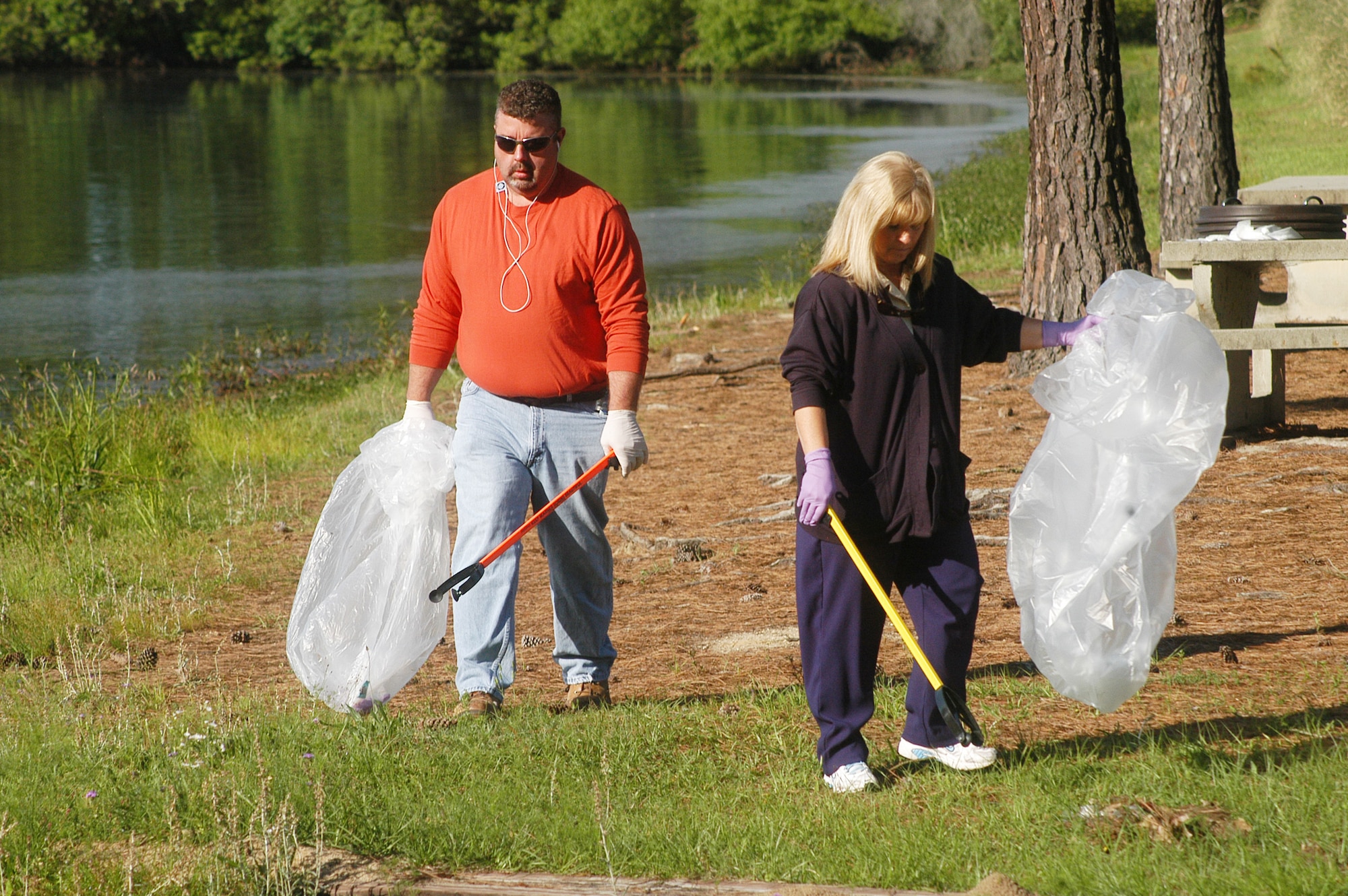 Griff Cox and Nita Crump, 78th Civil Engineer Group, pick up trash and debris around Scout Lake Wednesday. The clean-up was part of the Robins Air Force Base Earth Day Celebration events. (U. S. Air Force photo by Sue Sapp)