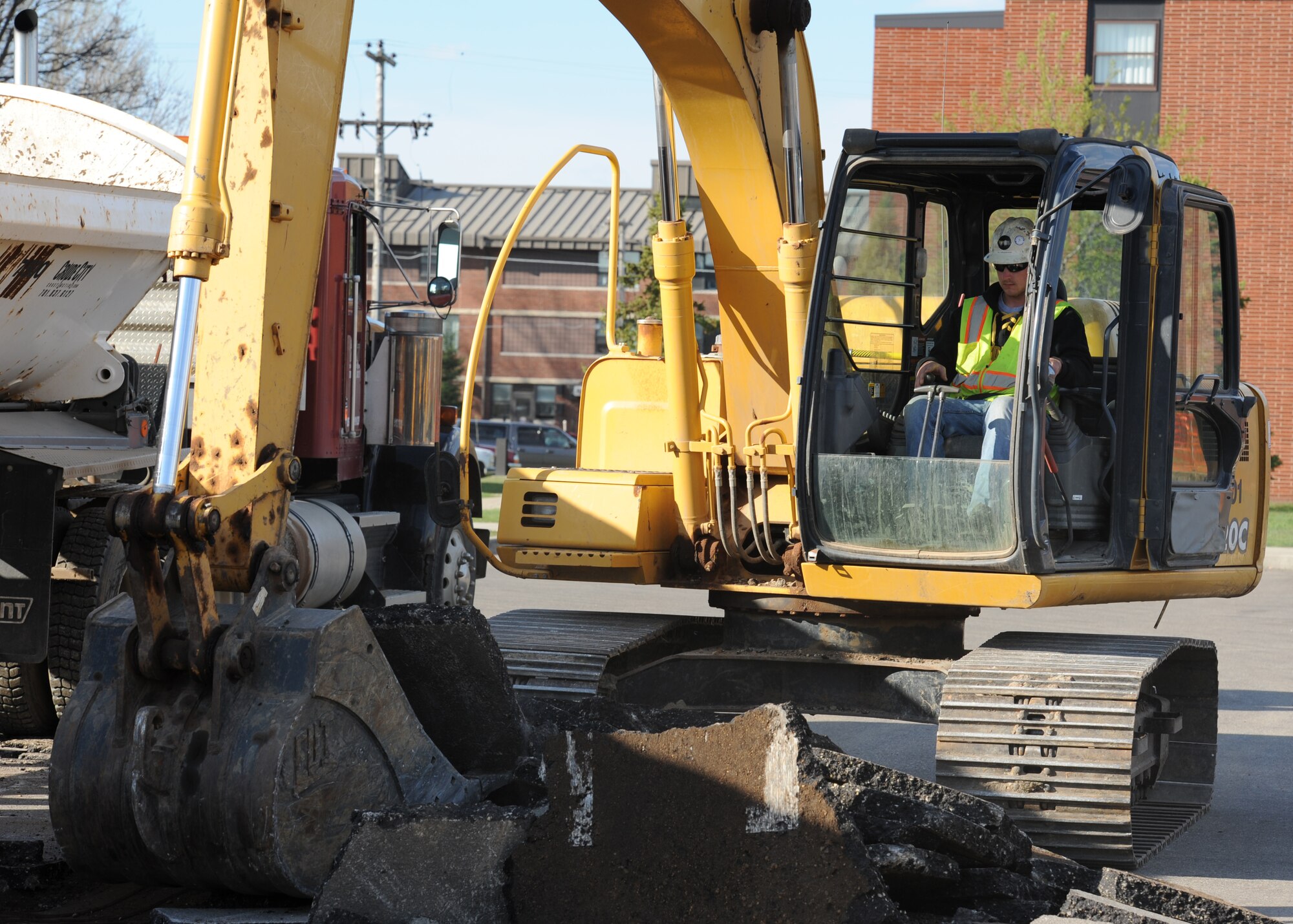 MINOT AIR FORCE BASE, N.D. -- Will Wasserburger of Crude City Construction of Minot, N.D., tears out asphalt with a backhoe as part of the construction of new dormitories here April 24. This construction is a 540 day project, which will provide for a better standard of living for Airmen. Wasserburger has been working for Crude City Construction for the past 10 years. (U.S. Air Force photo/Airman 1st Class Andrew Crawford)