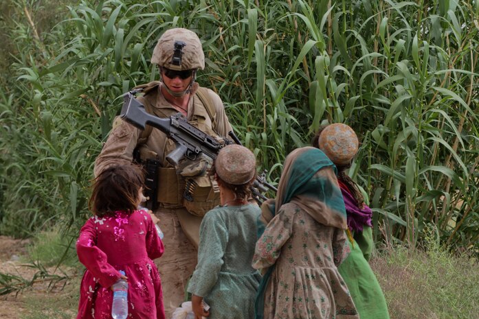 Lance Cpl. Brandon Debruler, a squad automatic weapon gunner with Weapons Company, 2nd Battalion, 6th Marine Regiment, hands bottled water to Afghan children, during a partnered patrol, April 26, 2012. Marines with 2nd Bn., 6th Marine Regiment, participated in Operation High Noon 15 with Afghan National Army soldiers with 1st Kandak, 1st Brigade, 215th Corps. The three-day operation cleared Trek Nawa, an area between the Marjah and Nawa district.::r::::n::::r::::n::::r::::n::