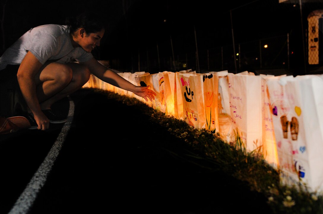 Daniela Pimentel, a member of the 6MCD Pacesetter group, lights a luminaria bag during a Relay for Life function at Beaufort Middle School, SC, Apr. 27.  Relay For Life participants, survivors and caregivers remember loved ones lost to cancer and honor those battling the disease through this ceremony.::r::::n::