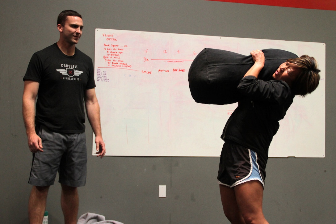 Former infantry officer Mike Jones, owner of CrossFit Minneapolis and CrossFit St. Paul, watches Gunnery Sgt. Alice Park, Recruiting Substation Duluth, practice bag cleans during a CrossFit re-certification course April 27. For additional imagery from the event, visit www.facebook.com/rstwincities.