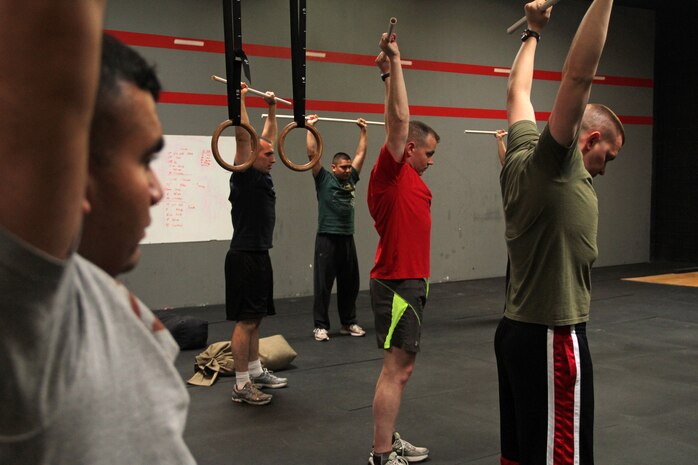 Marines from various offices within Recruiting Station Twin Cities practice push-press exercises during a CrossFit re-certification course April 27. For additional imagery from the event, visit www.facebook.com/rstwincities.