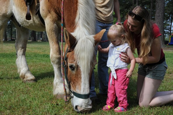 Patricia Wischmann helps her daughter Emmalynn, 2, pet a horse during the Month of the Military Child information fair on Seymour Johnson Air Force Base, N.C., April 21, 2012. During the fair, the children were given the opportunity to ride or pet horses, ponies, and a donkey. Patricia, spouse of Airman Wischmann a 333rd Aircraft Maintenance Unit crew chief is from Flagstaff, Ariz. (U.S. Air Force photo/Airman 1st Class John Nieves Camacho/Released)