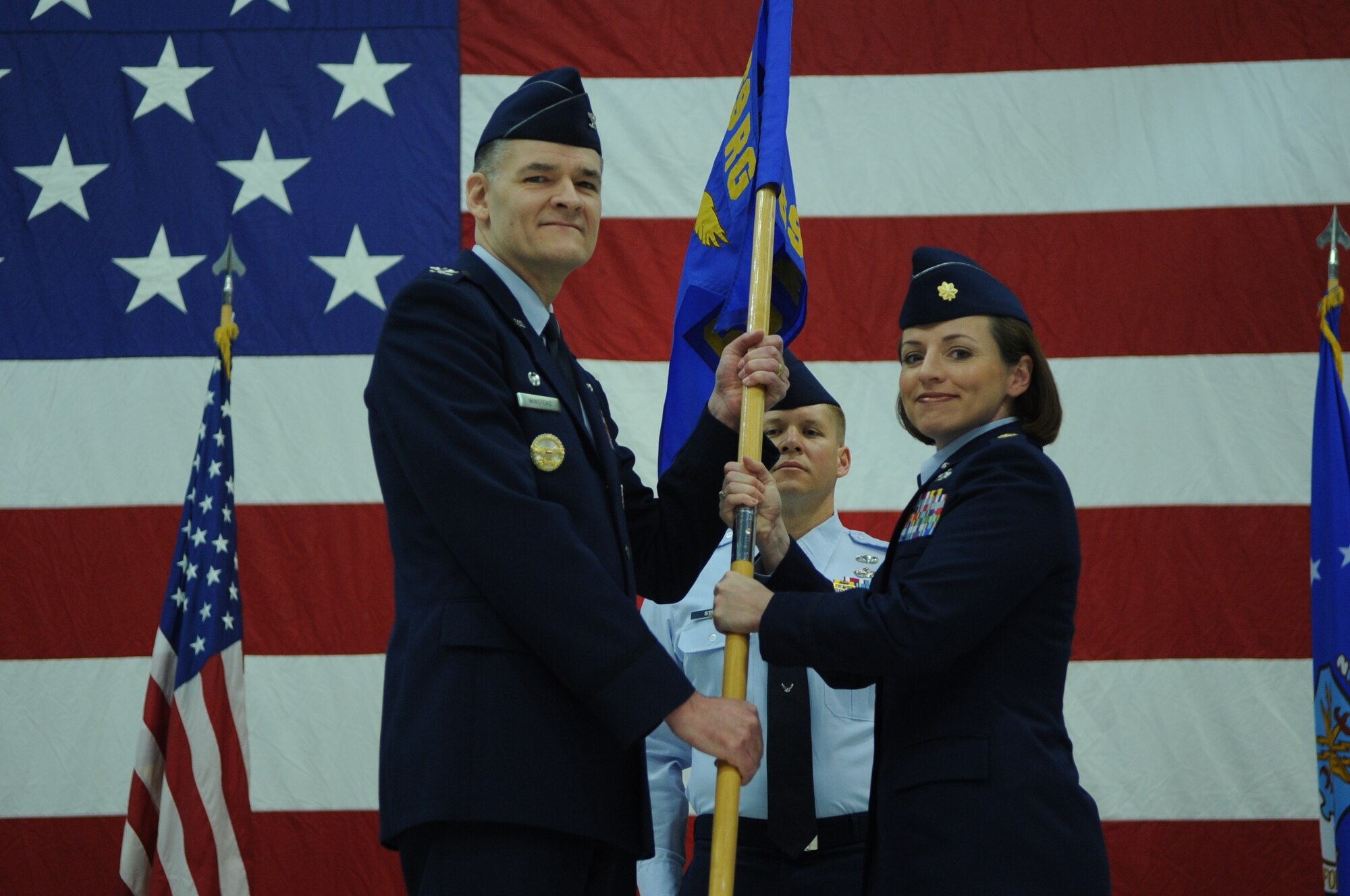 Col. J. Scott Winstead, 69th Reconnaissance Group commander, hands the 69th Maintenance Squadron guidon to incoming commander Maj. Stacey L. Ferguson during an Assumption of Command ceremony at Grand Forks Air Force Base, N.D., on April 27, 2012. Ferguson will serve as the first permanent commander of the squadron, which stood up in September 2011. (U.S. Air Force photo by Staff Sgt. Amanda N. Grabiec)
