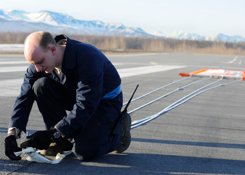 Air Force Tech. Sgt. Jessie Hatfield prepares a banner for operation on the flight line at Joint Base Elmendorf-Richardson, Alaska, April 24. The 3rd Maintenance Squadron crash recovery team conducts banner operations, allowing a target banner to be flown behind a Cessna for F-22s to exercise shooting the 20mm gun. This allows the pilots to train for real world combat. Hatfield is the noncomissioned officer in charge of the wheel and tire maintenance flight. (U.S. Air Force photo/Staff Sgt. Robert Barnett)