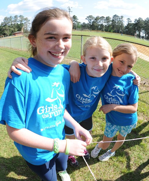 Girls on the Run teammates smile and hug before a physical training session on Seymour Johnson Air Force Base, N.C., April 24, 2012. The girls have been training for more than two months and will participate in a 5k-run celebrating the end of their training on April 27. (U.S. Air Force photo/Airman 1st Class Aubrey Robinson/Released)