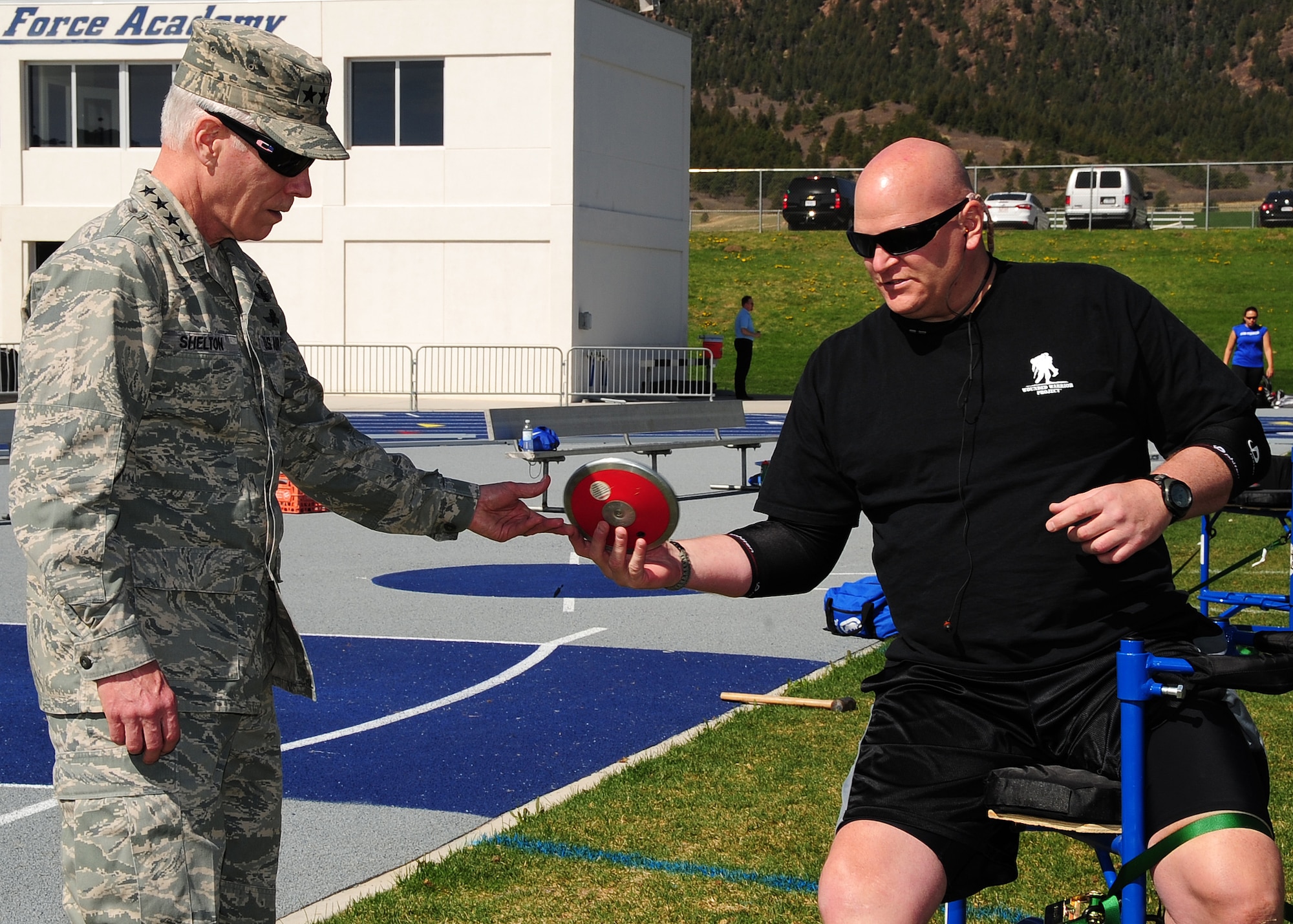 Gen. William L. Shelton, Commander, Air Force Space Command, takes a discus from Tech. Sgt. Keith Sekora who is competing in the Warrior Games at the U.S. Air Force Academy, Colo. April 25. The Air Force encourages wounded warriors to reach for and achieve a rich and productive future, to defeat their illness or injury to maximize their abilities and know that they can have a rich and fulfilling life beyond what has happened to them in service to their nation. (U.S. Air Force photo/Duncan Wood)