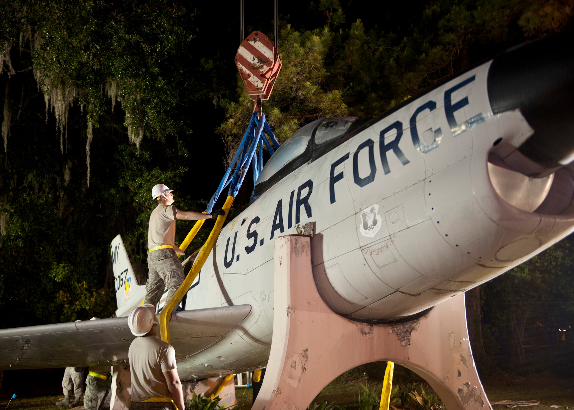 Airmen from Moody Air Force Base, guide crane straps that assisted in the lifting of an F-86L Sabre onto a flatbed trailer from its memorial mount located on the corner of Ashley Street and Woodrow Wilson Drive in Valdosta, Ga., April 24, 2012. The aircraft has long been a landmark in the town, but is now relocated to Moody where it will be refurbished and placed at the George W. Bush Air Park at Moody Field to commemorate the Flying Tigers heritage. (U.S. Air Force photo by Senior Airman Eileen Meier/Released)